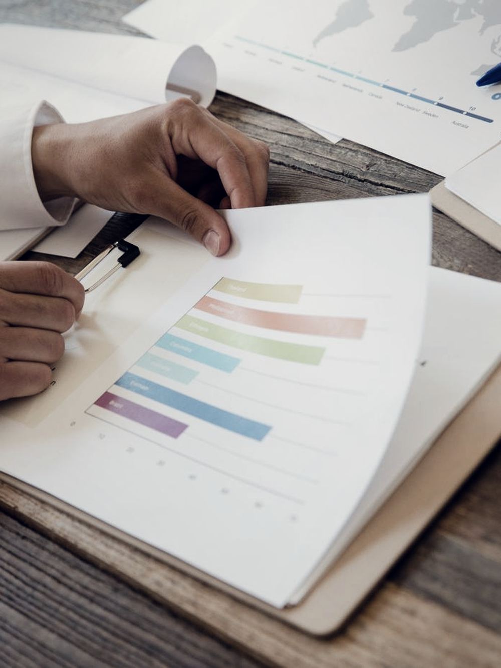 Hands comparing printed performance charts across a table.